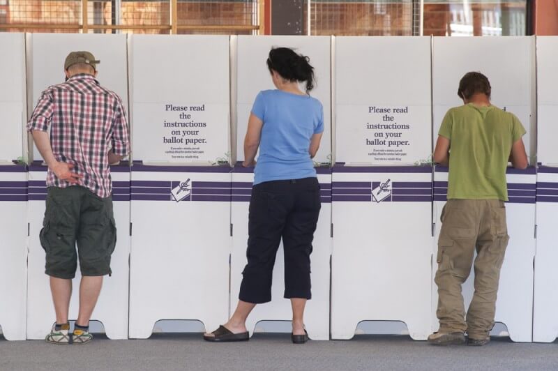 Australian voters at electoral commission voting booths filling out ballot papers